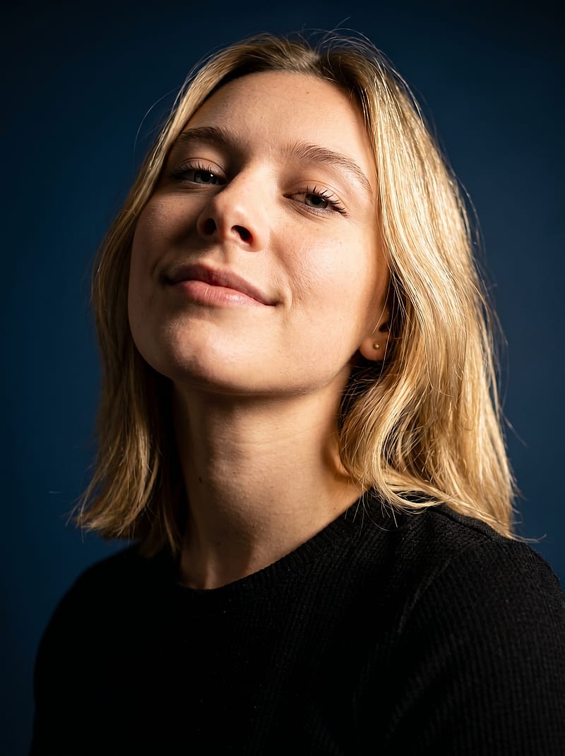 Cinematic studio portrait with high-contrast lighting on a rich blue background, confident professional pose.