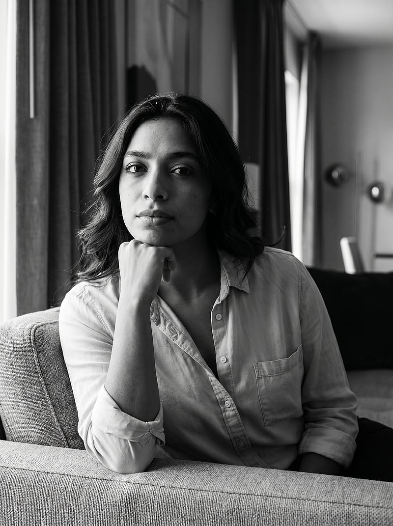 Black and white editorial portrait on a sofa, Rembrandt side lighting with sophisticated office atmosphere.
