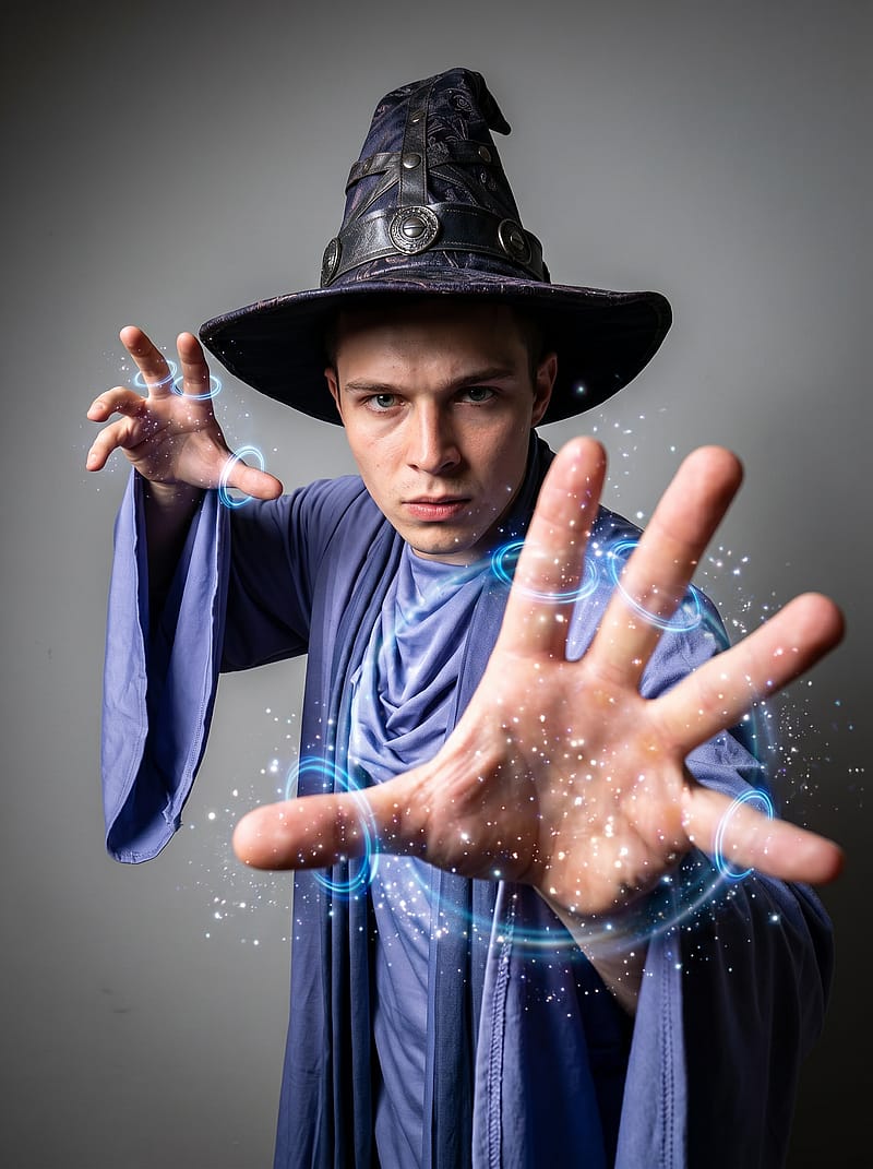 Powerful wizard in flowing robes casting a spell with hand extended toward camera, dramatic studio lighting.